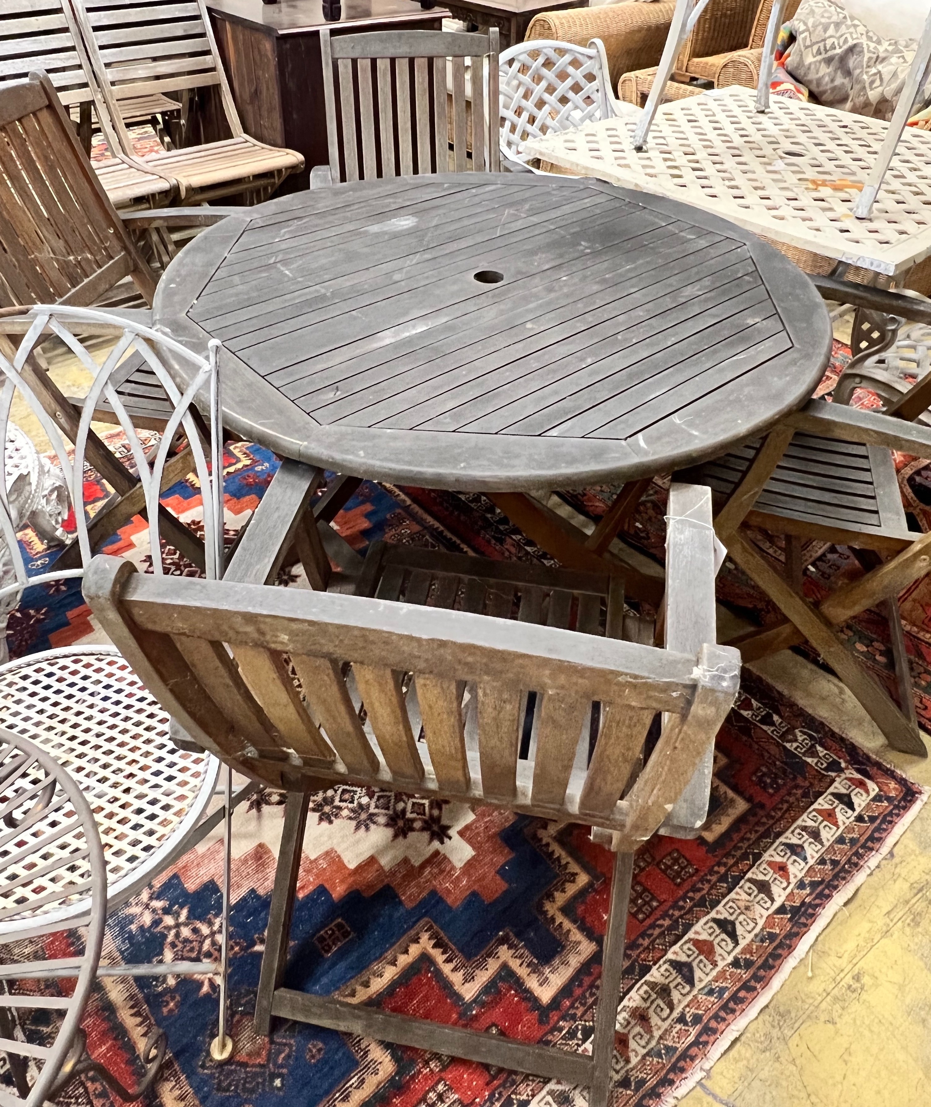 A circular weathered teak folding wooden garden table, diameter 110cm height 72cm, together with four elbow chairs